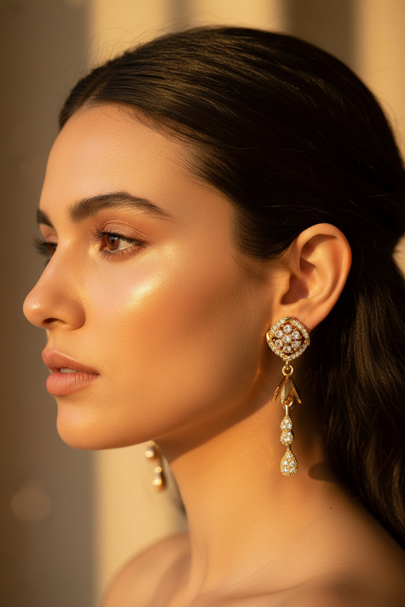 Close-up of rose gold bird-motif earrings featuring white stones and a tiered bell drop.