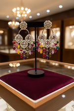 Close-up of silver plated Kundan earrings with white central stones and colorful artisan beads on a jewellery display.