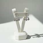 Close-up of the 1cm Amara silver AD earrings featuring a large heart stud and three dangling pavé-set heart charms.