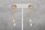 Close-up of the Vortex rose gold polish earrings on a display stand, highlighting the spiral stone setting and the dual-chain white stone drops.