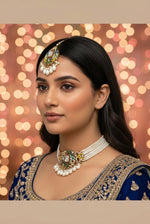Close-up shot of a woman wearing a handcrafted brass choker set featuring vibrant multi-colored sugar stones and white Kundan embellishments. The necklace is finished with dangling pearl drops, paired with matching statement earrings.