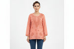 A model wearing a peach-colored short kurti featuring intricate tonal embroidery around the neckline and front, with an inset highlighting the square hemline detail