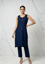 A model wearing the navy blue handcrafted sleeveless Chanderi silk Chikankari co-ord set, posing against a white marble studio wall.