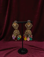 Decorative earrings with colorful beads on a stand against a dark background