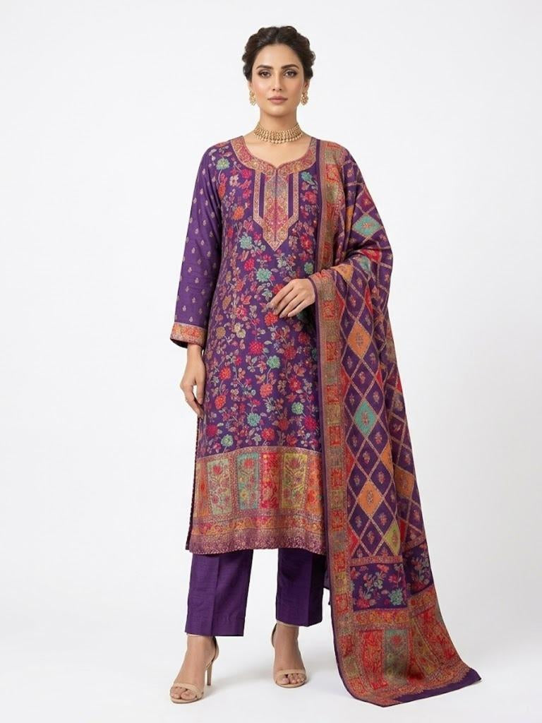 Model standing against a pure white background wearing a deep purple silk kurta set featuring intricate Kanni embroidery and zari work, paired with raw silk trousers and a patterned dupatta.