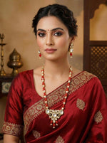 Detail shot of a girl wearing the elegant Kundan earrings featuring drop-style red stones and pearl accents.