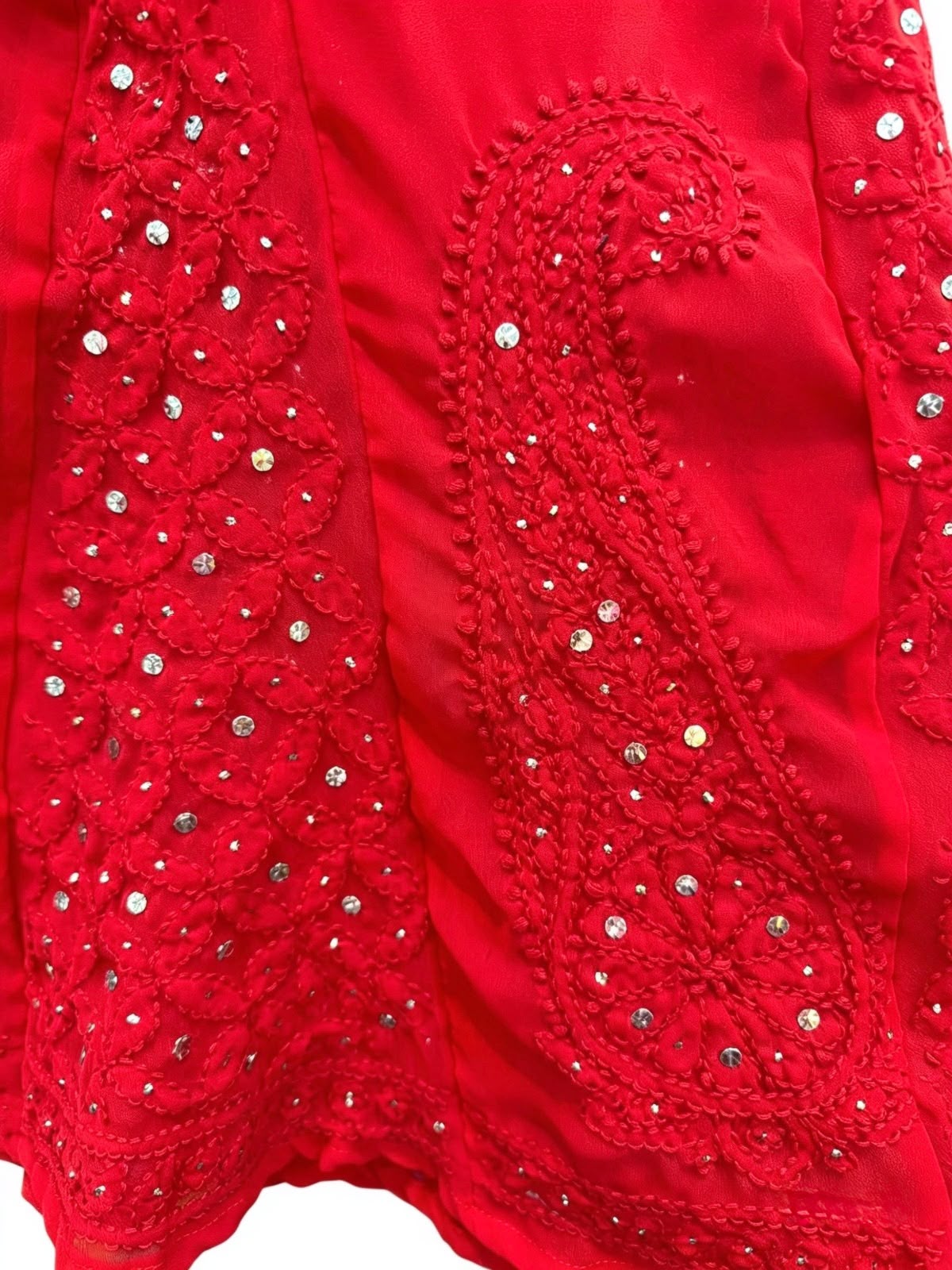 Close-up view of intricate red paisley embroidery and delicate sequin work on a crimson sharara fabric.