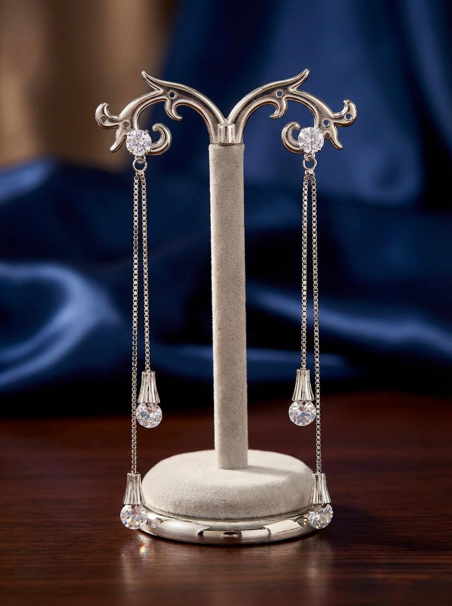 Detailed shot of the 10cm Celestial silver AD statement earrings on a display stand, showing the triple-tier stone drop design.