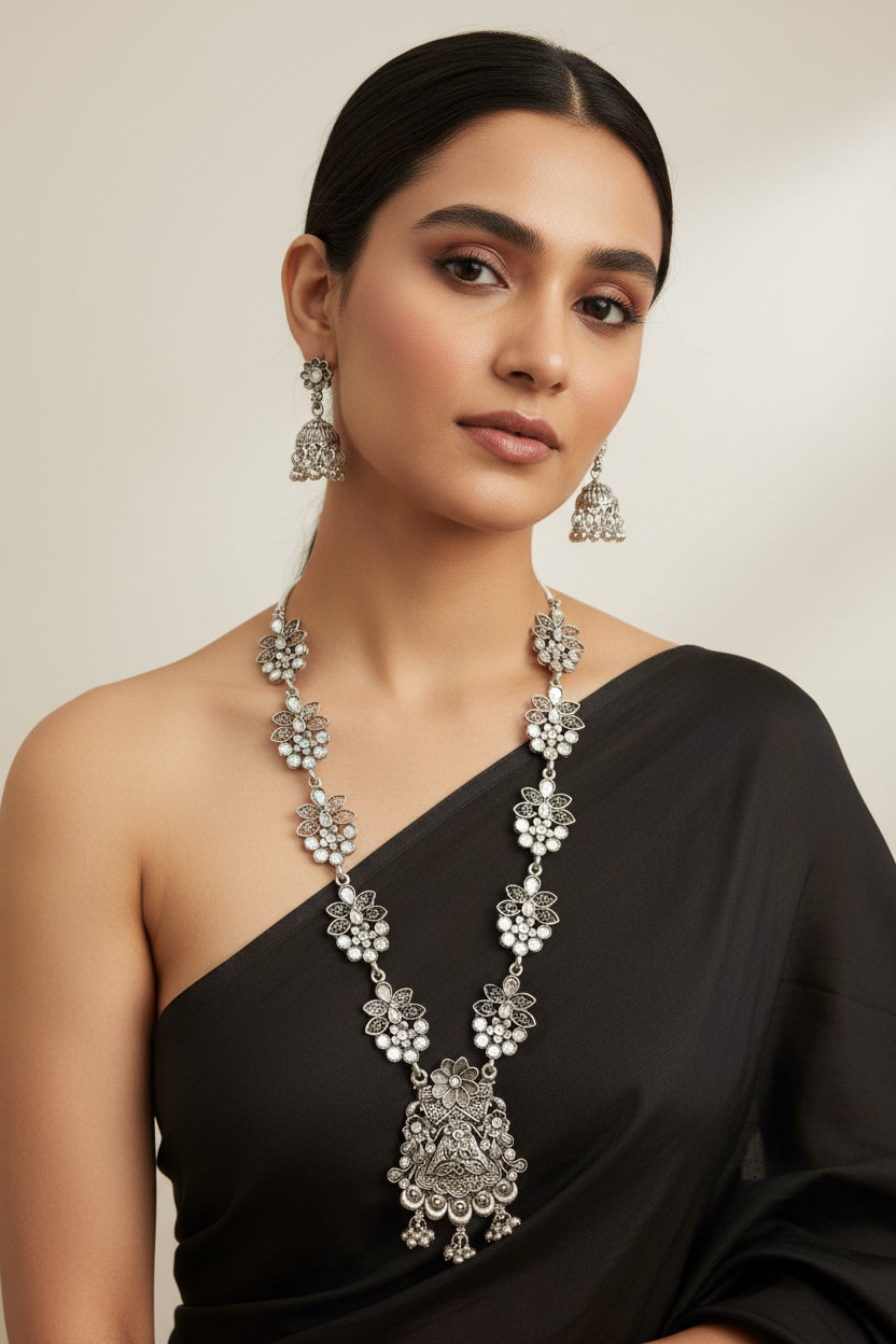 Detailed shot of the intricate floral carvings and central mirror inlays on the oxidised pendant and earring set.