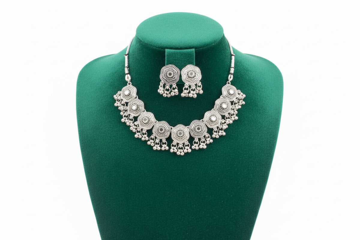 Detailed shot of the symmetrical floral engravings and reflective mirror centers on the antique silver-finish necklace.