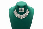 Detailed shot of the symmetrical floral engravings and reflective mirror centers on the antique silver-finish necklace.