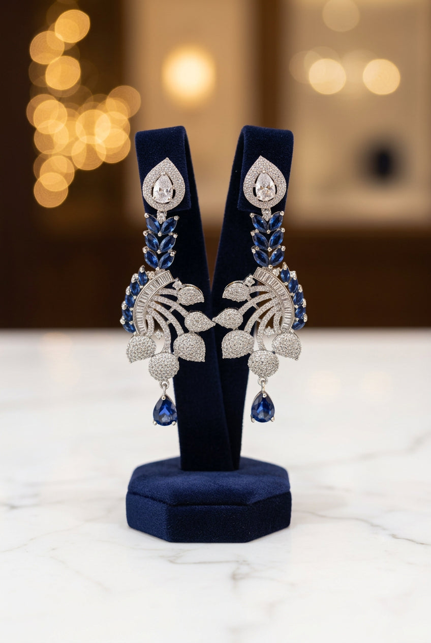 Earrings featuring leaf elements, with blue sapphire stones and American diamonds. Party wear posh jewellery set.