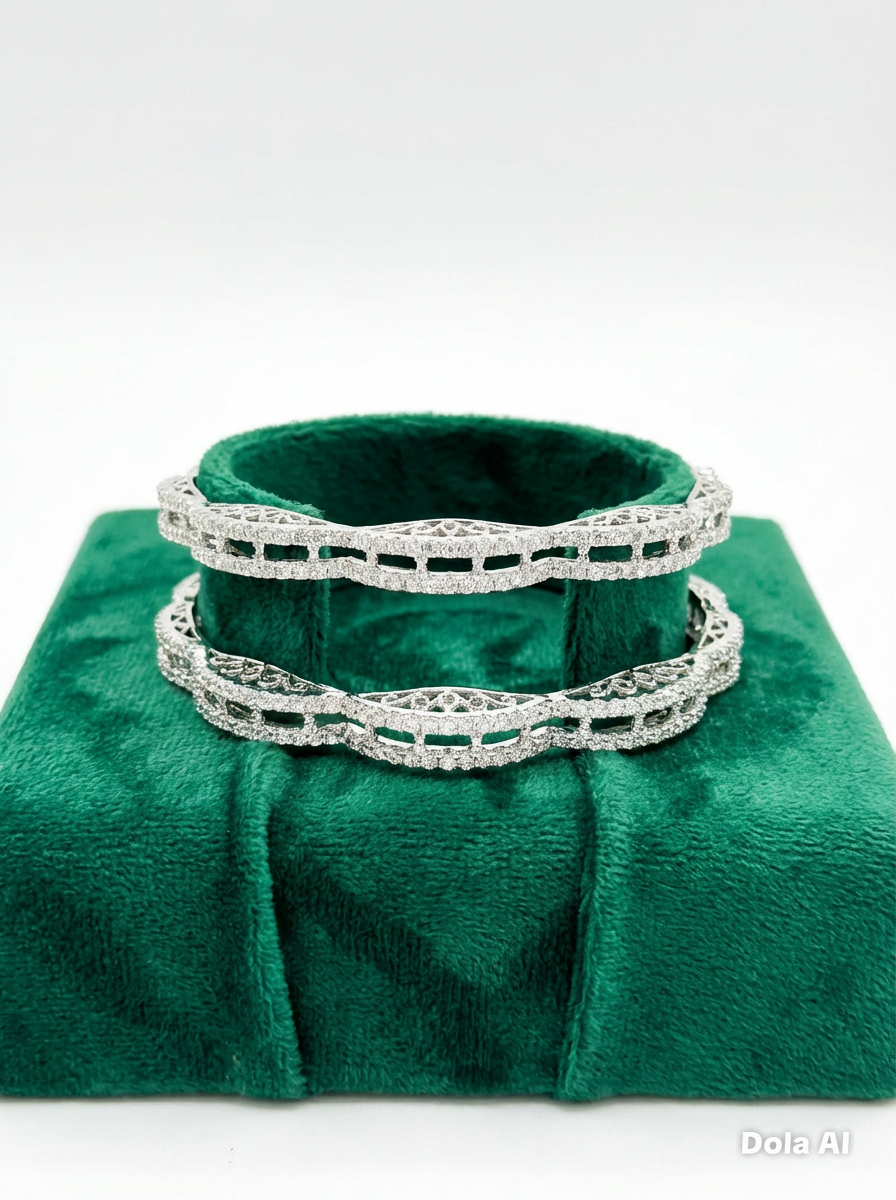 A pair of silver-toned American diamond bangles with a unique wavy, scalloped edge and intricate open-work lattice design, displayed on a plush emerald green velvet jewelry stand.
