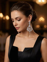 Close-up of elegant statement drop earrings featuring detailed crystal settings, worn with a black formal dress.
