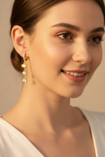 Elegant gold-tone drop earrings featuring three cascading square-cut clear crystals suspended from a delicate crystal-accented hoop.
