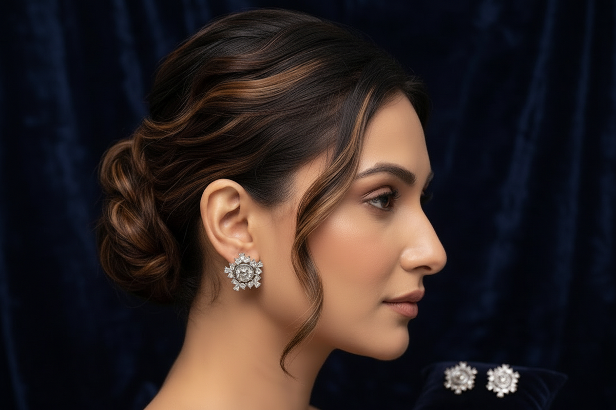 A woman in profile wearing a sparkling silver-toned floral stud earring, with matching earrings displayed on a dark navy velvet surface. The background is a matching dark navy velvet fabric.