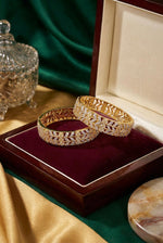 A pair of premium dual-tone American Diamond bangles featuring an intricate gold floral lattice and silver leaf vine design, elegantly displayed inside a maroon velvet luxury jewelry box.