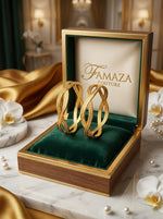 A pair of interlocking swirl-design micro gold-plated bangles displayed inside a luxury Famaza Couture wooden and velvet jewelry box.