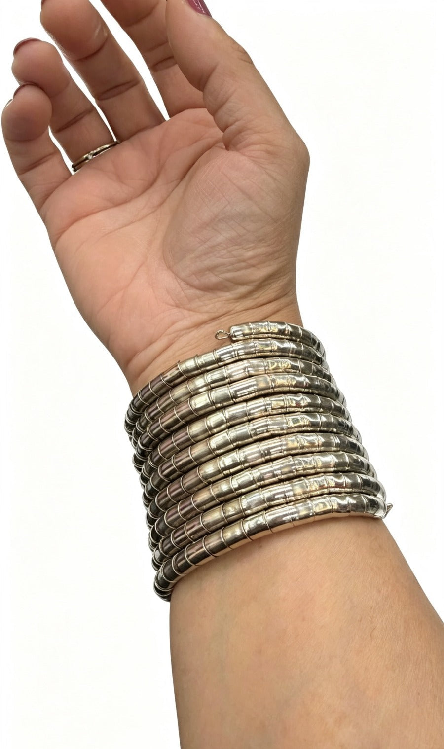 A close-up view of a wrist wearing a multi-strand silver-toned segmented slip-on spiral cuff bracelet against a plain white background.
