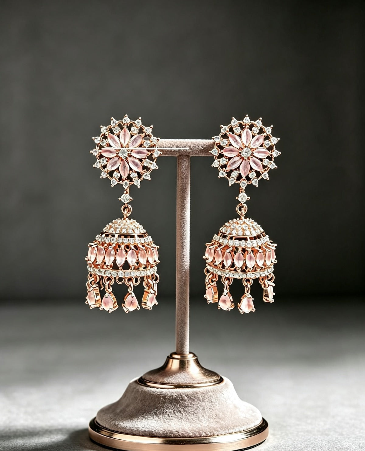 FC Rose Gold Pastel Pink Floral CZ Jhumka Earrings beautifully displayed on a velvet boutique stand against a neutral background.