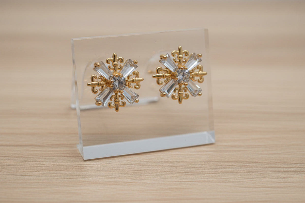 Festive statement stud earrings with a central round crystal and radiating gold filigree snowflake arms.