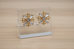 Festive statement stud earrings with a central round crystal and radiating gold filigree snowflake arms.