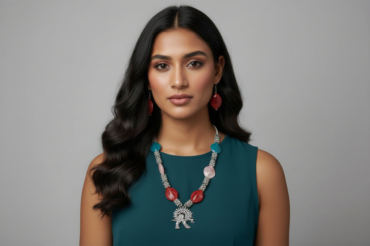 Woman wearing a necklace with red and blue stones against a gray background