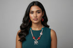 Woman wearing a necklace with red and blue stones against a gray background