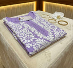 Folded purple kurti with white floral pattern on a beige surface, surrounded by jewellery.