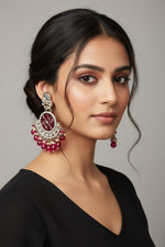 Front view of large maroon Chandbali earrings with crystal halos and hanging red droplets worn by our model.