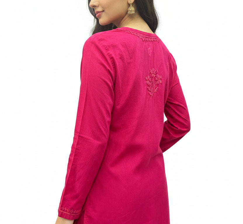 Model wearing a fuchsia pink cotton short kurti showing the back view, featuring a subtle embroidered floral motif below the neckline.