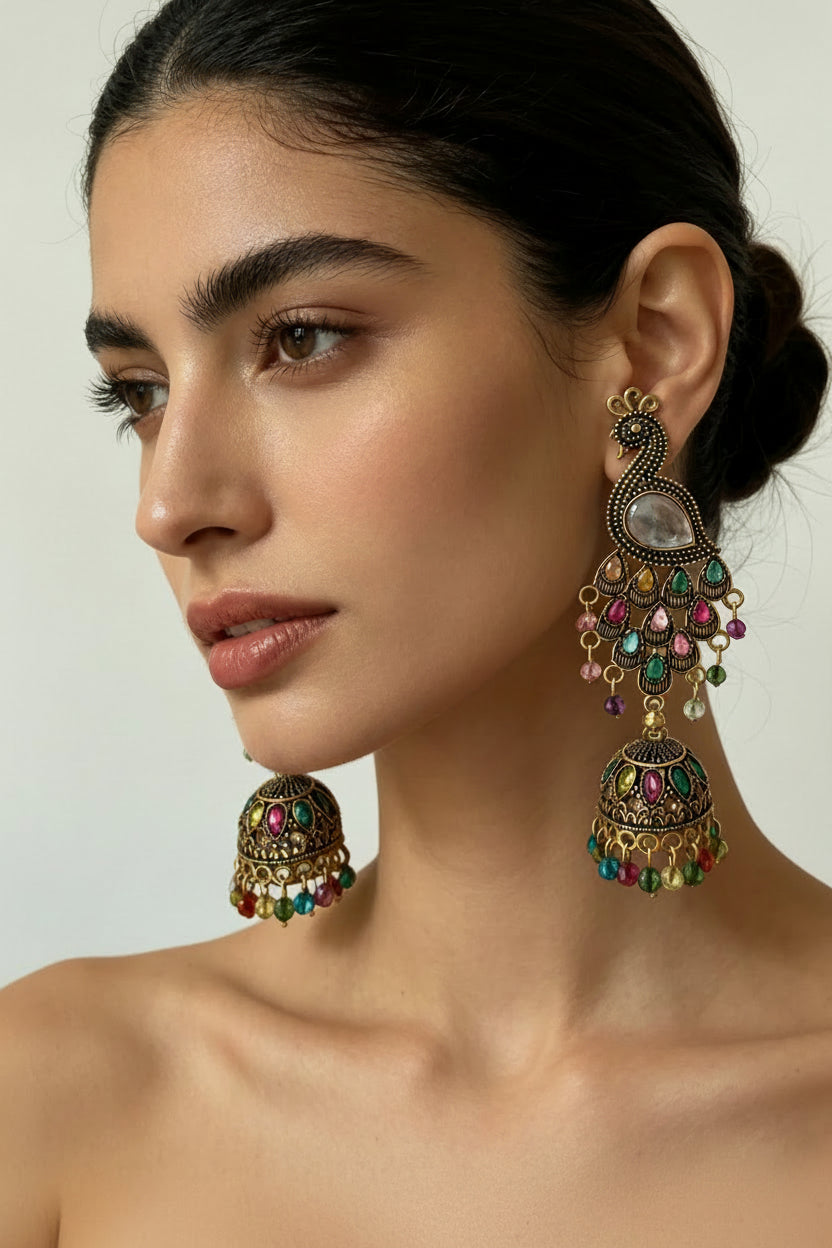 Profile view of a model wearing Gilded Peacock Silhouette antique gold-plated multistone jhumka earrings, highlighting the detailed peacock design and colorful beaded bell drops.