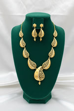 Gold plated paisley filigree necklace with matching earrings displayed on black velvet stand, pure white background.