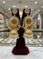 Gold and pearl jewellery set held by a hand with a blurred background