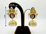 Gold earrings with face design on a black stand with measurements.