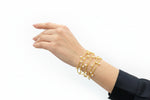 Gold pearl bracelet on a wrist with a clothing rack in the background