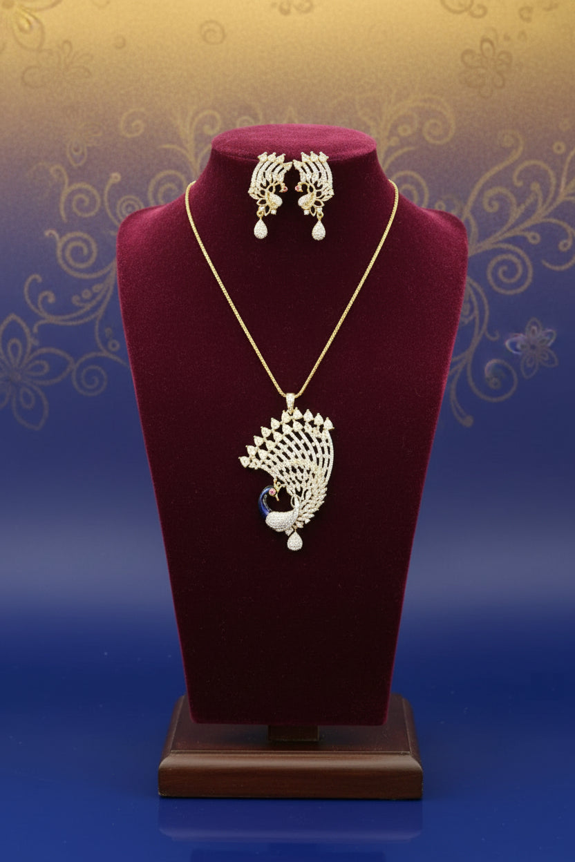 Gold plated a set of peacock-shaped pendant in golden chain with peacock-shaped earrings. The pendant is detailed with blue enamel and has sparkling crystal white AD stones embellishments.