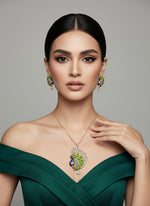 Gold polished a peacock full open wings design pendant with vibrant green, blue, and gold enamel accents, along with white ad stones sparkling embellishments, accompanied by matching earrings, displayed on a black mannequin necklace stand. Party wear jewellery set.