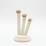 Golden heart-shaped stud earrings in graduated sizes, each featuring a central crystal on a stand.