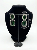 Green gemstone earrings on a black bust with measurements displayed.