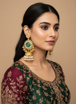 Gold and green decorative item held by a hand with a blurred background