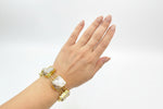 Hand wearing a gold bracelet with large stones on a white background