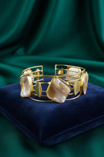 A gold-plated bracelet featuring various shaped Mother of Pearl stones on a light background.