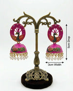 Hot pink 5.5cm peacock jhumka earrings displayed on a dark velvet card highlighting the 3cm width.