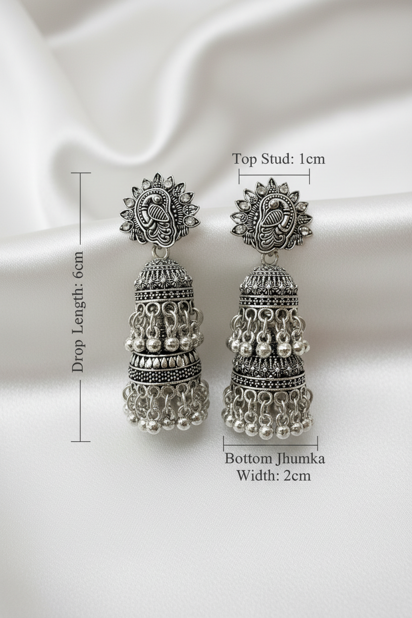 Detailed size chart of oxidized silver jhumka earrings: peacock‑embellished top stud (1cm width), total drop length 6cm, bottom jhumka width 2cm, with multi‑layered bell design and dangling bead accents on a plain white background.