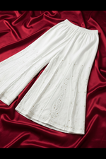 Flat lay view of a wide-leg ivory cotton sharara featuring intricate white-on-white Bakhiya embroidery and antique gold Kaamdani detailing.