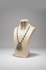 Jewellery set on a mannequin bust with 'Artisan Silver Collection' sign in a store setting.