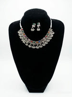 Jewelry set with necklace and earrings on a black stand against a white background