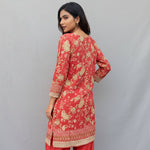 Model is showing the rear view of this coral pink colour printed kurti and plain pants