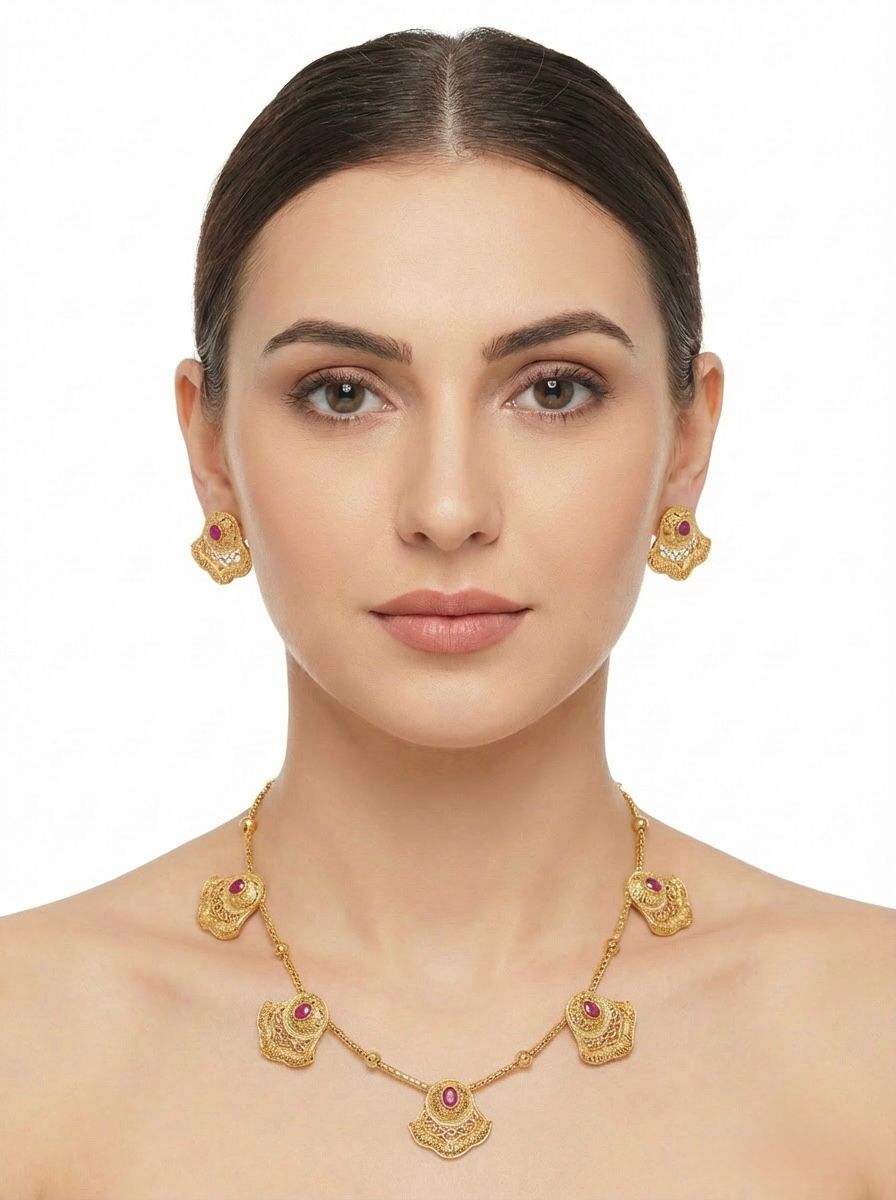 Model is wearing Antique gold brass metal necklace and stud earrings with ruby red central stones.